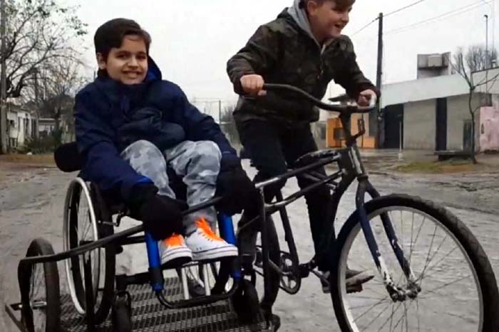 Menino cria bicicleta com sidecar para levar primo em cadeira de rodas