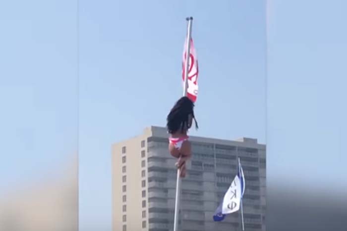 Mulher sobe em mastro para tirar bandeira e se dá mal 