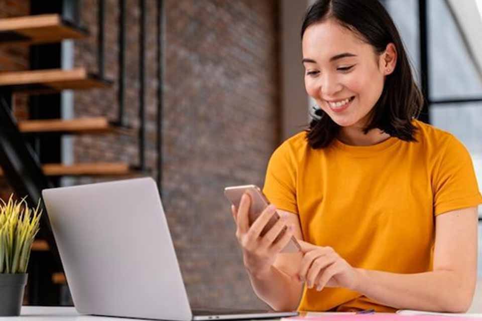 Free photo young woman using phone while attending online class