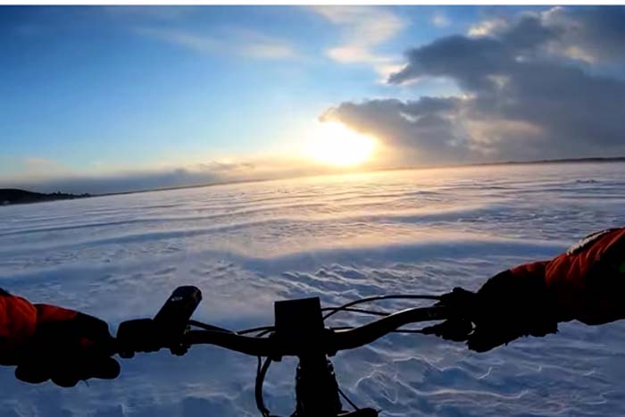 Ciclista passeia tranquilamente em lago congelado 