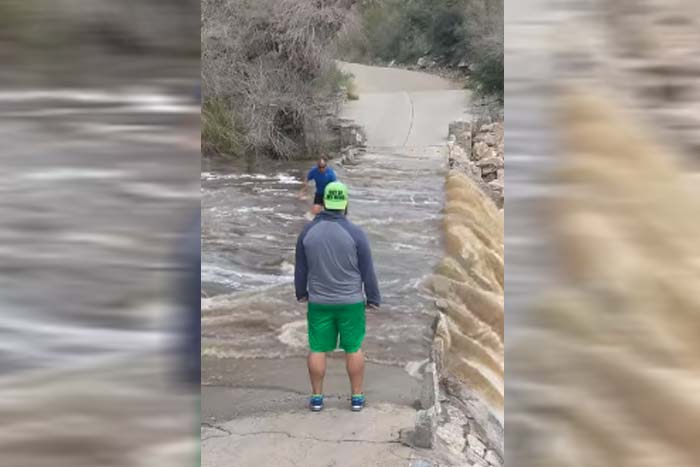 Homem arrisca a vida atravessando ponte alagada 
